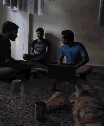 three men are sitting on the floor in a dark room