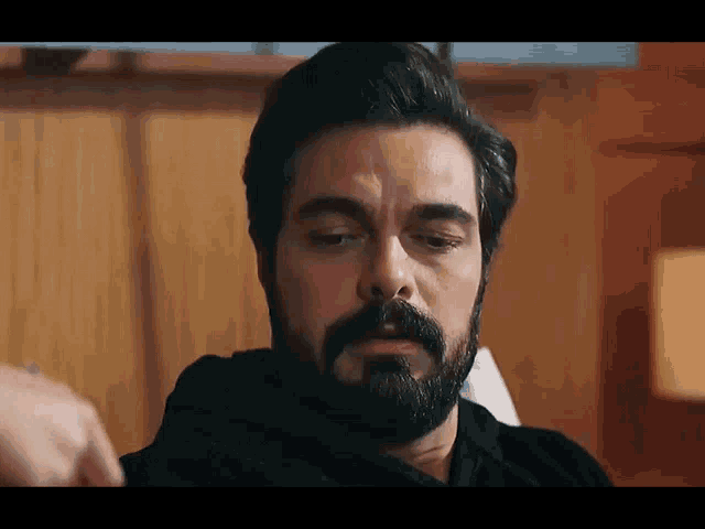 a man with a beard is sitting in a chair and looking down