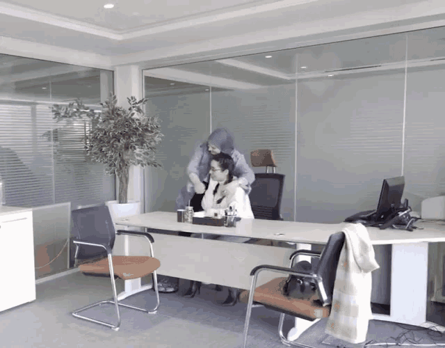 a woman standing next to a woman sitting at a desk with a computer