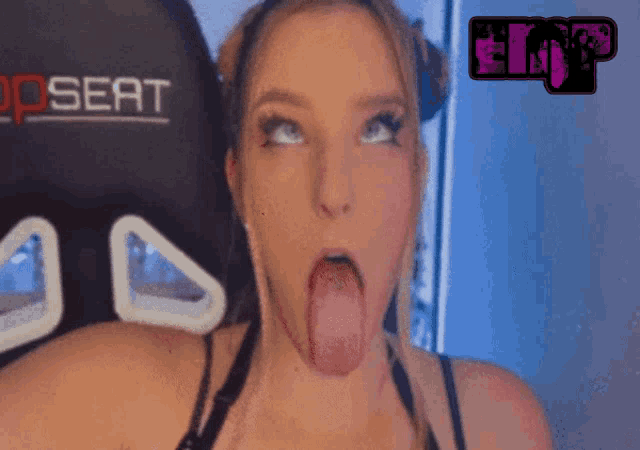 a woman is sticking her tongue out in front of a top seat gaming chair
