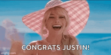 a woman wearing a pink hat is waving at the camera and saying congrats justin .