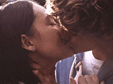 a man and a woman are kissing and the man is wearing a blue sweatshirt