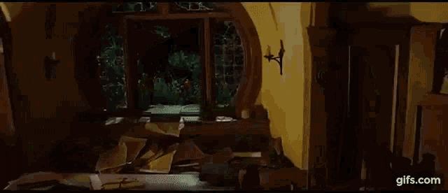 a person is laying on a bed in a dark room with a stained glass window behind them .