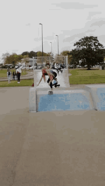 a person is riding a skateboard down a ramp in a park
