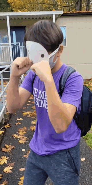 a boy wearing a mask and a purple shirt that says ' te mousine ' on it