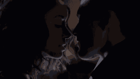 a man and woman are kissing in a dark room .