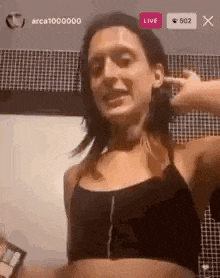 a woman in a crop top is covering her ears with her hands while standing in front of a tiled wall .