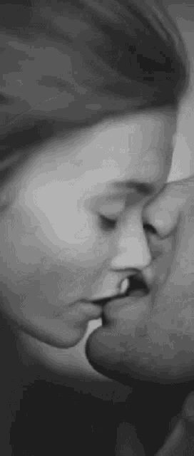 a black and white photo of a man and woman kissing each other .