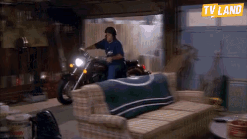 a man riding a motorcycle in a garage with a tv land sign above him