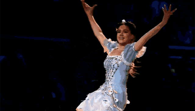 a woman is dancing on a stage in a blue dress .