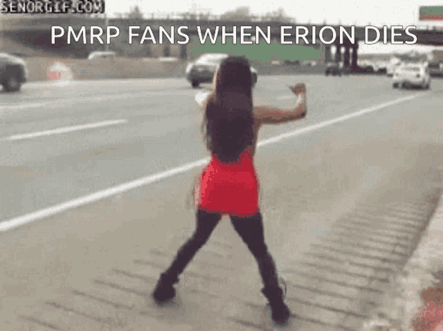 a woman in a red dress is dancing on the side of a highway