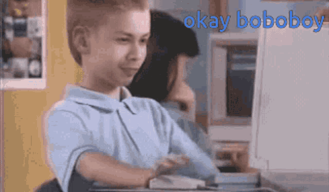 a young boy is sitting in front of a computer with the words okay boboboy above him