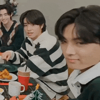 a group of young men are sitting at a table with plates of food and drinks .