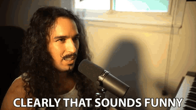 a man singing into a microphone with the words clearly that sounds funny behind him