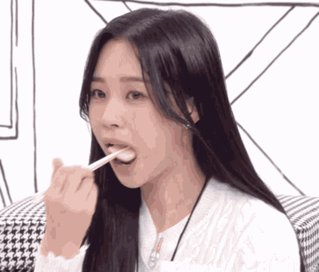 a woman is eating something with chopsticks and a necklace around her neck