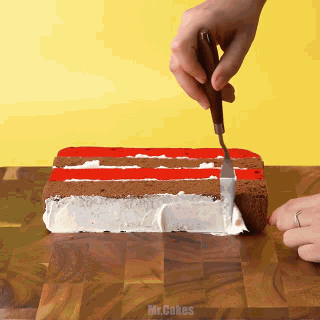 a person spreading frosting on a cake that says mr.cakes on it