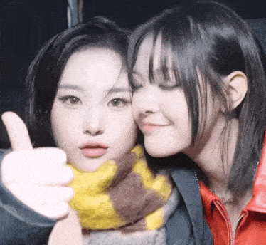 two girls are posing for a picture and one is giving a thumbs up sign .