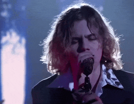 a man singing into a microphone with his eyes closed