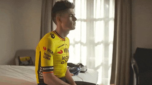 a man sitting on a bed wearing a yellow jersey that says lease on it