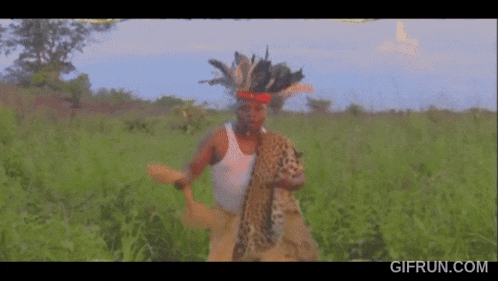 a man in a white tank top holding a leopard in a field
