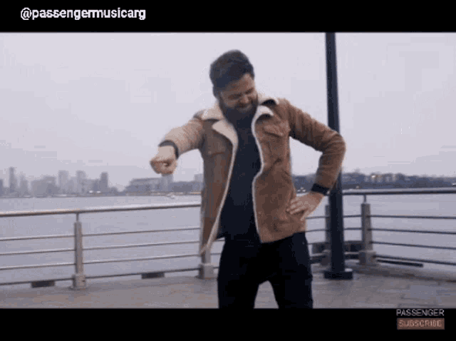 a man in a brown jacket is dancing in front of a body of water with the words passenger subscribe below him
