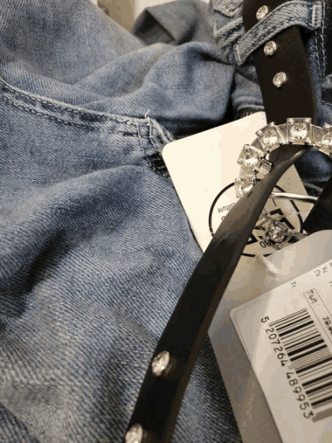 a black belt with rhinestones sits on top of a blue denim shirt