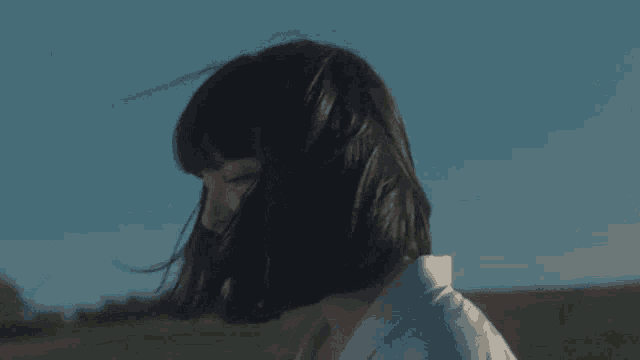 a woman with short hair is standing in a field with her eyes closed .