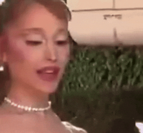 ariana grande is wearing a white dress and a pearl necklace .