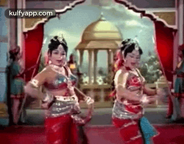 a couple of women are dancing in a room in front of a building .