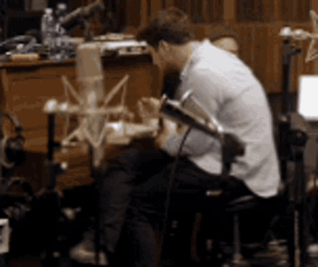 a man is sitting in front of a microphone playing a guitar