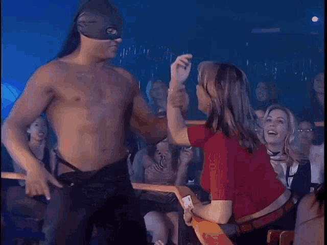a shirtless man in a mask is dancing with a woman