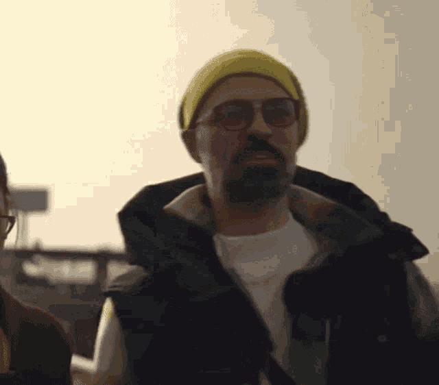 a man with glasses and a beard wearing a yellow hat