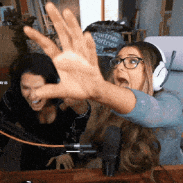 a woman wearing glasses and headphones is reaching out her hand in front of a microphone