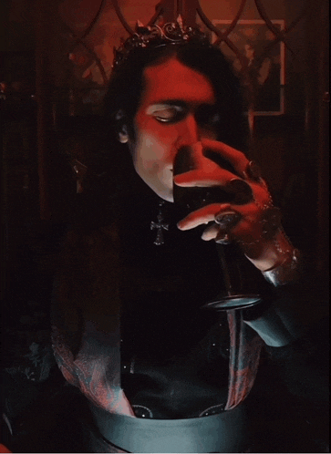 a man with a crown on his head is holding a glass in his hand