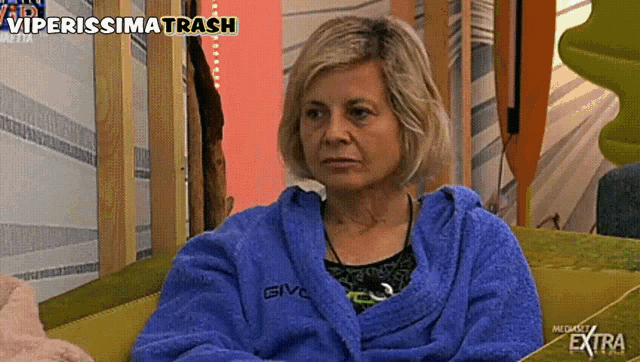 a woman wearing a blue givova robe is sitting on a couch