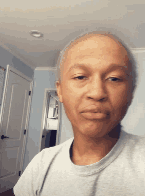 a man in a grey shirt looks at the camera with a serious look on his face