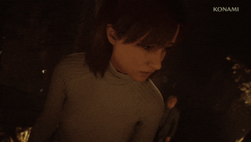a woman stands in front of a fire with konami written on the bottom right