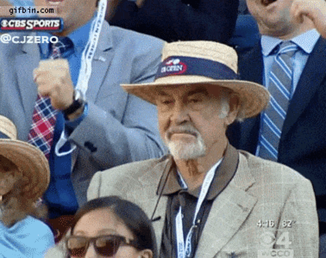 a man wearing a straw hat with a cbs sports logo behind him