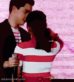 a man and a woman are kissing in front of a pink background with the words aldubmode tumblr on the bottom right