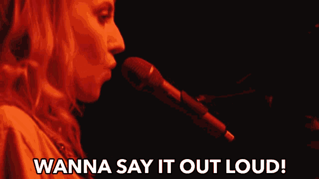 a woman singing into a microphone with the words wanna say it out loud