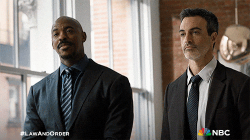 two men in suits and ties standing next to each other with a nbc logo on the bottom