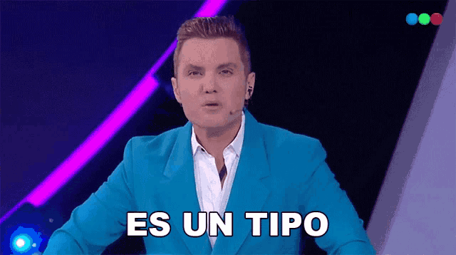 a man in a blue suit stands in front of a microphone and says es un tipo