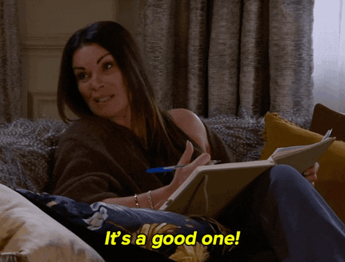a woman sits on a couch holding a notebook and a pen and the words it 's a good one