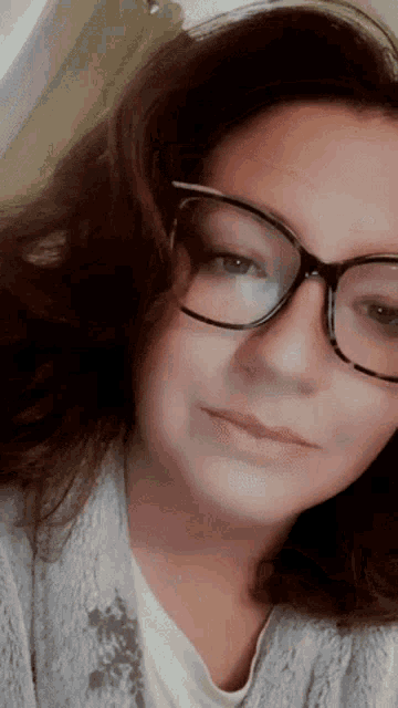 a close up of a woman wearing glasses and a gray sweater