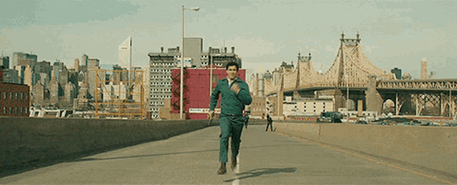 a man in a green shirt is running on a highway with a bridge in the background