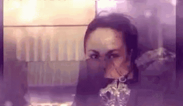 a close up of a woman 's face with a purple background behind her .