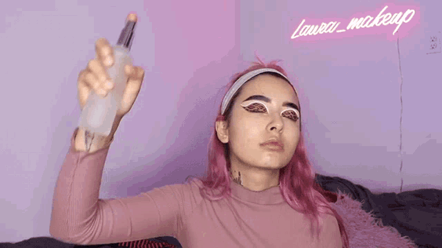 a woman with pink hair is spraying something on her face