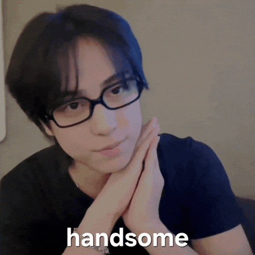 a person wearing glasses and a black shirt with the word handsome written on it
