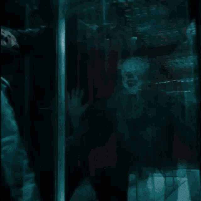 a close up of a clown behind a broken glass door .