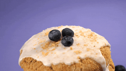 a close up of a cake with blueberries on top on a purple background